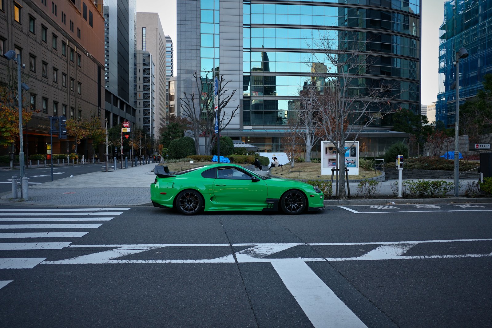green toyota supra at a tokyo crossing