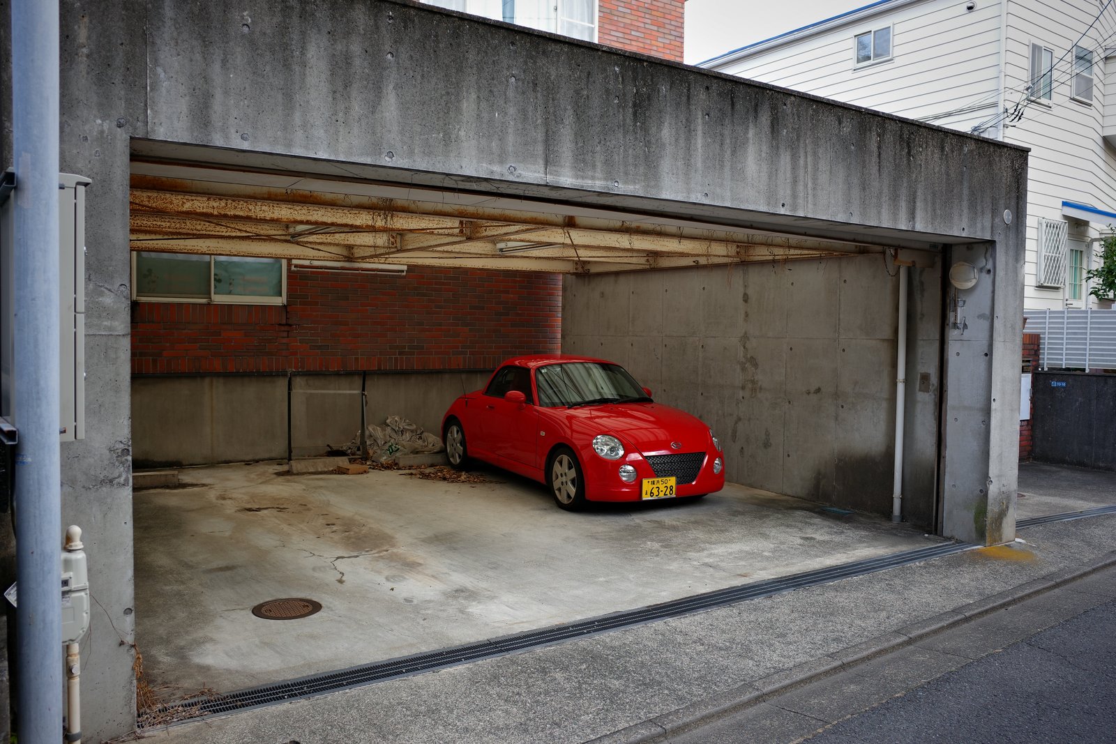 red daihatsu copen in a concrete garage