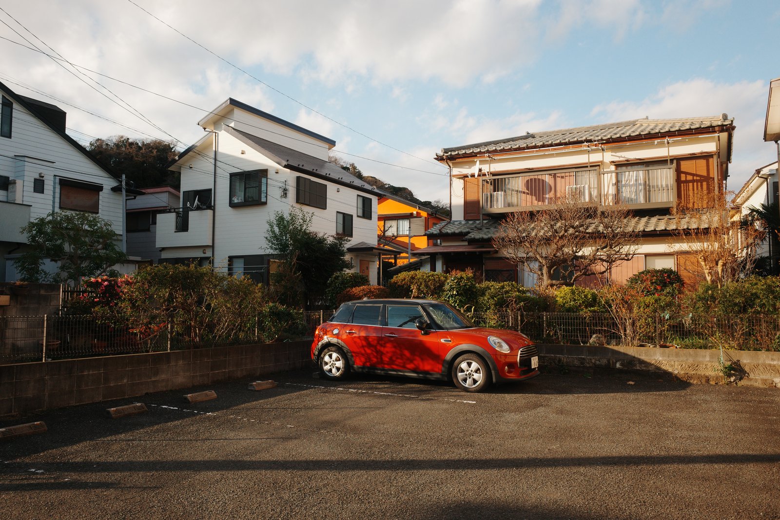 red mini parked in a suburban lot at dusk